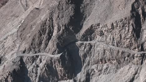 pakistani trucks travel on dangerous paved road along the mountain, transport goods via karakoram highway