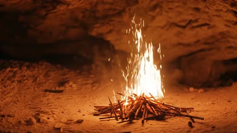 un pequeño fuego de campamento arde brillantemente en una cueva