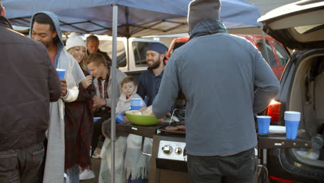 slow motion shot of sports fans tailgating in parking lot