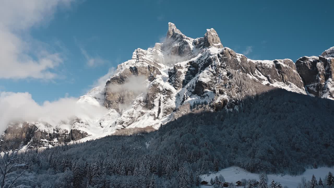 una vista aérea del circo du fer à cheval mientras está cubierto de nieve durante un frío invierno, volando hacia el pico tenneverge bañado por el sol con la proximidad a las puntas de los pinos