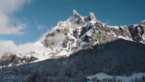 una vista aérea del circo du fer à cheval mientras está cubierto de nieve durante un frío invierno, volando hacia el pico tenneverge bañado por el sol con la proximidad a las puntas de los pinos