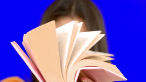 mujer hojeando un libro rosa en una pantalla azul