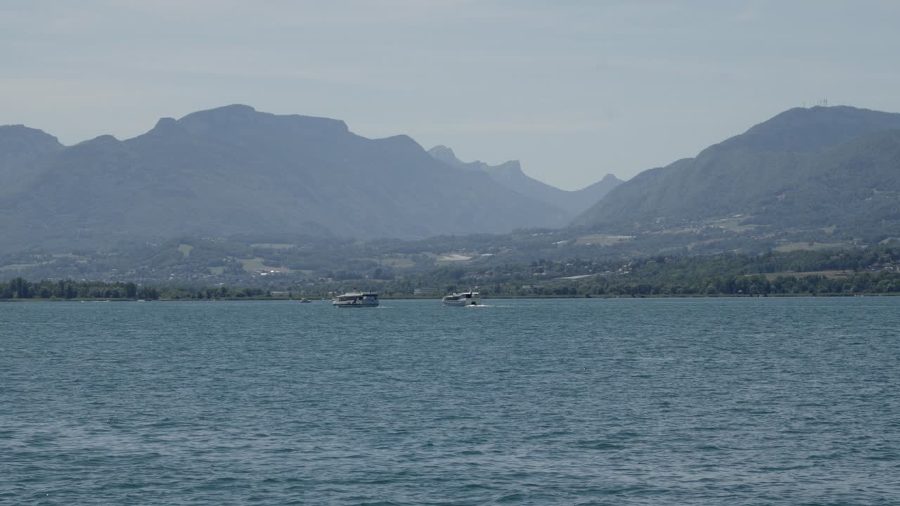 Panoramic static shot water flow in alpine lake, mountains motorboats background