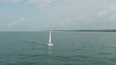 vista aérea de un velero blanco en el tranquilo mar báltico, yate de vela blanco en medio del mar sin límites, día soleado de verano, amplio seguimiento realizado