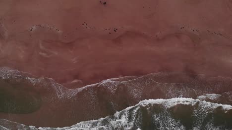 Vista-Aérea-De-Arriba-Hacia-Abajo-De-La-Playa-De-Arena-Vacía-Y-Solitaria-Con-Olas-Largas-En-Una-Puesta-De-Sol-De-Verano