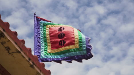 Whale-temple-colourful-flag-waves-against-cloudy-sunny-sky