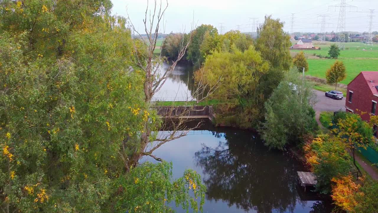 Aerial above the fortress of Haasdonk and surrounding agricultural fields with powerline towers in the distand landscape