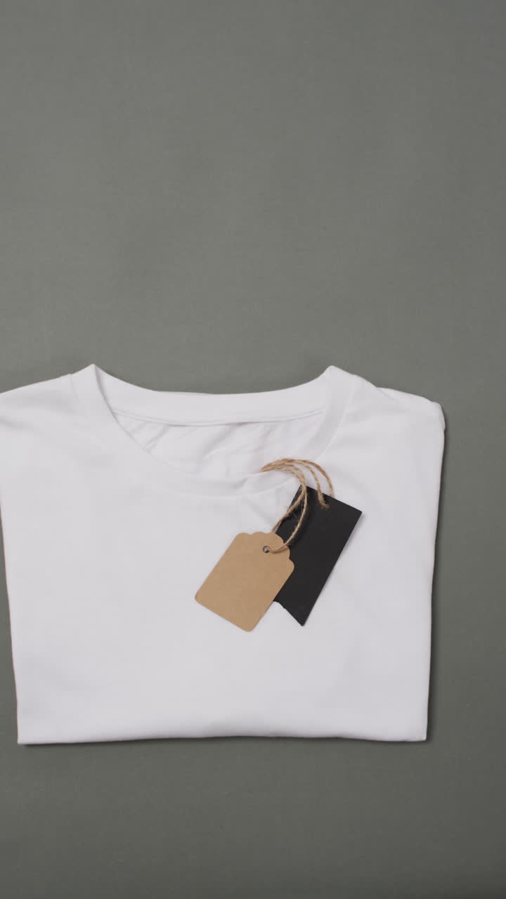 Vertical video of white t shirt with tags and copy space on grey background
