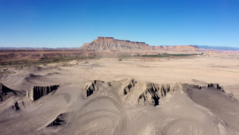 Huellas-De-Neumáticos-En-Swing-Arm-City,-Una-Zona-Todoterreno-En-Torrey,-Utah,-Con-North-Caineville-Mesa-En-Segundo-Plano-En-Un-Clima-Caluroso-Y-Soleado.