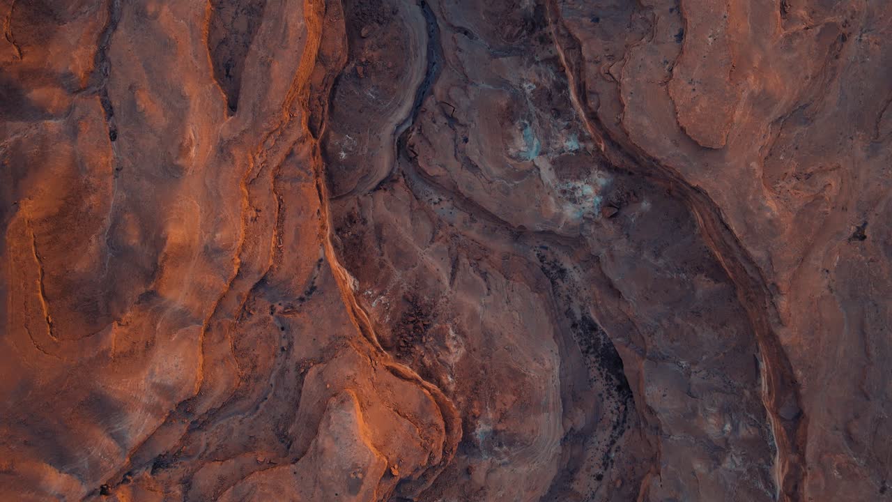 Red rocks in the desert with a black and white image of them. The red rocks are on a hillside where water may have flowed over them. The rocks are covered with moss, creating an interesting landscape.
