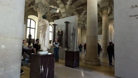 people observing sculptures in louvre museum, paris