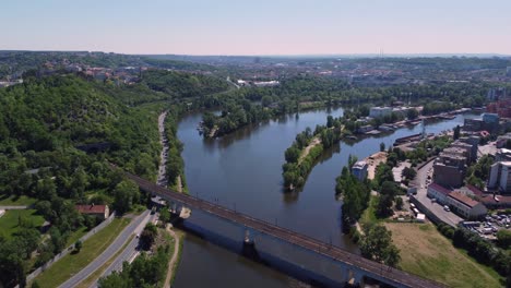aerial drone view of railway bridge crossing vltava river in prague, czech republic, sunny day traffic
