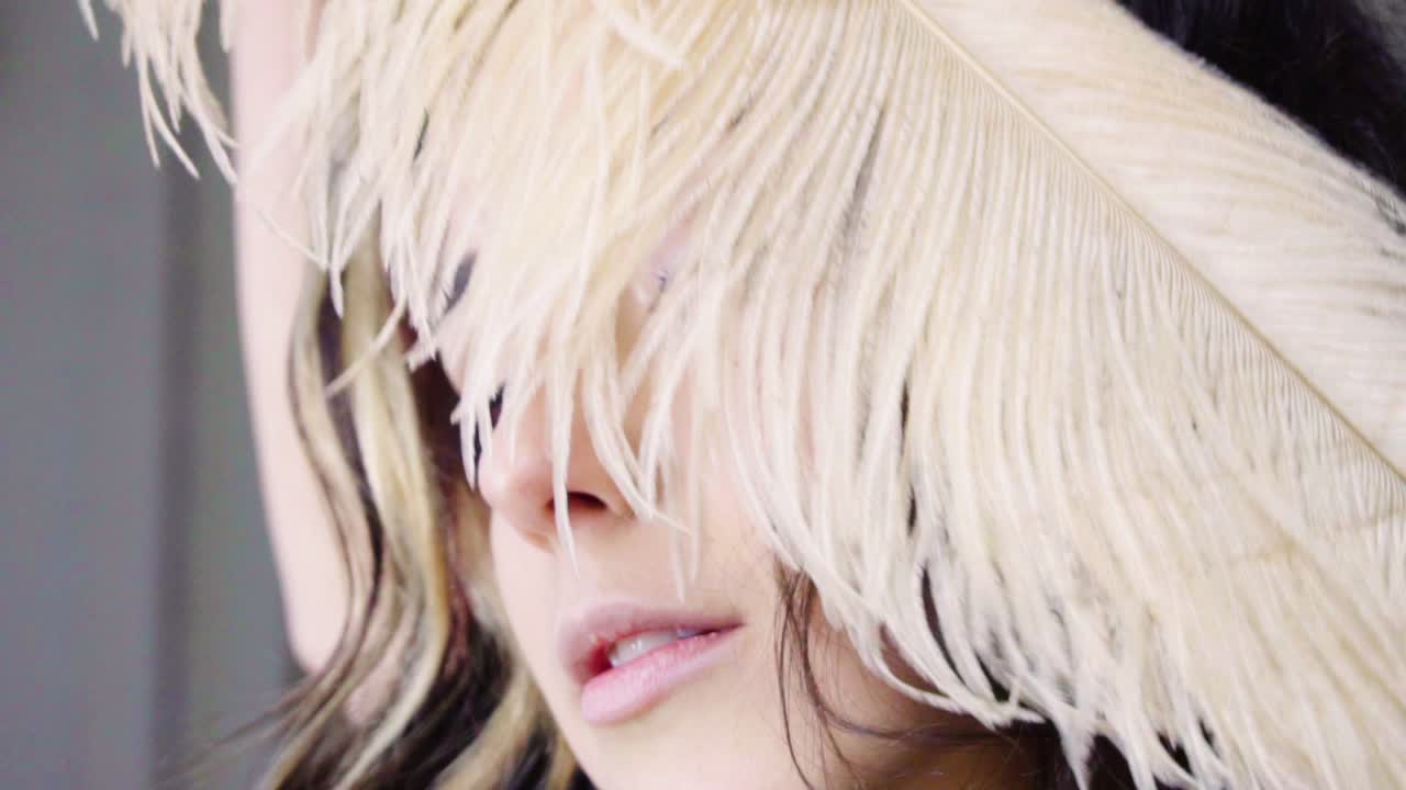 젊은 갈색 머리 여자 의상 파티에서 깃털을 통해 보이는