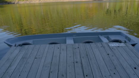 dolly shot of a wooden landing stage with a anchored boat on the local reservoir