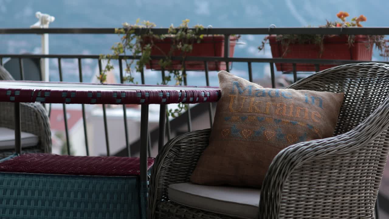 Furniture with cross stitch pillow in wicker chair at balcony Kotor Montenegro