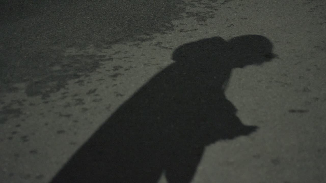 사람의 그림자는 밤에 거리에서 전화를 스크롤합니다.