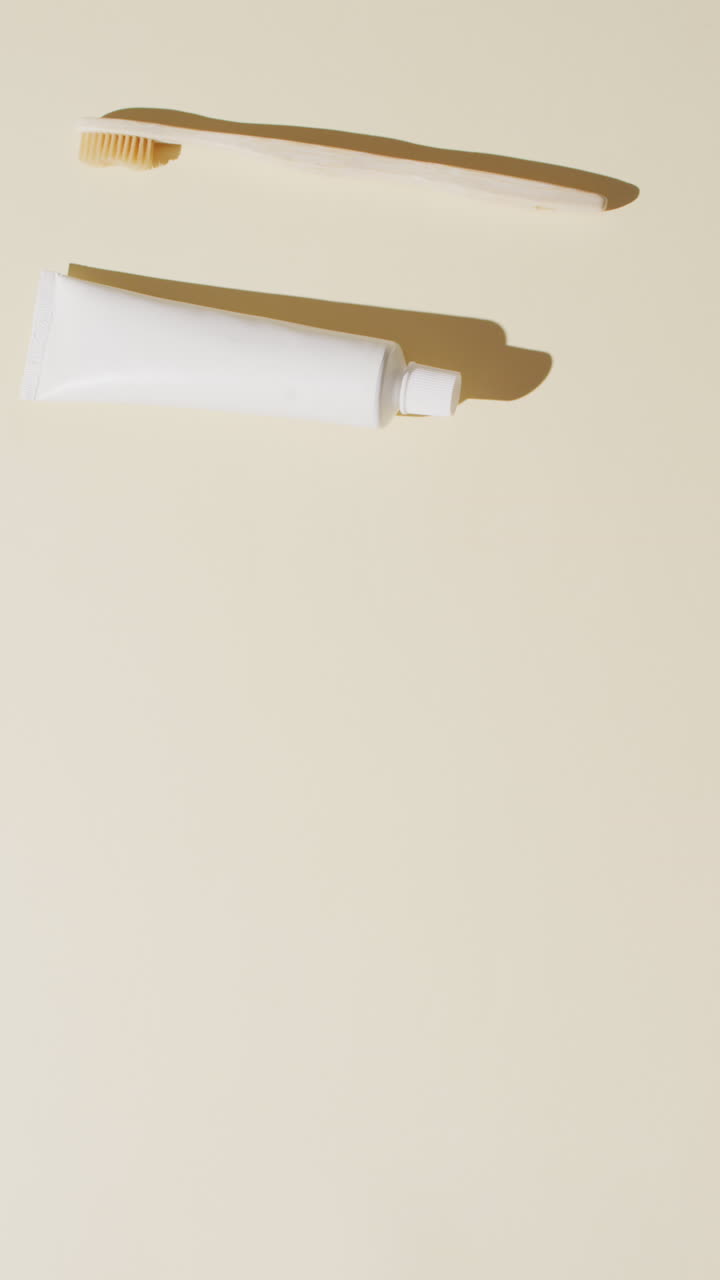 Vertical video of toothpaste and toothbrush on beige background with copy space