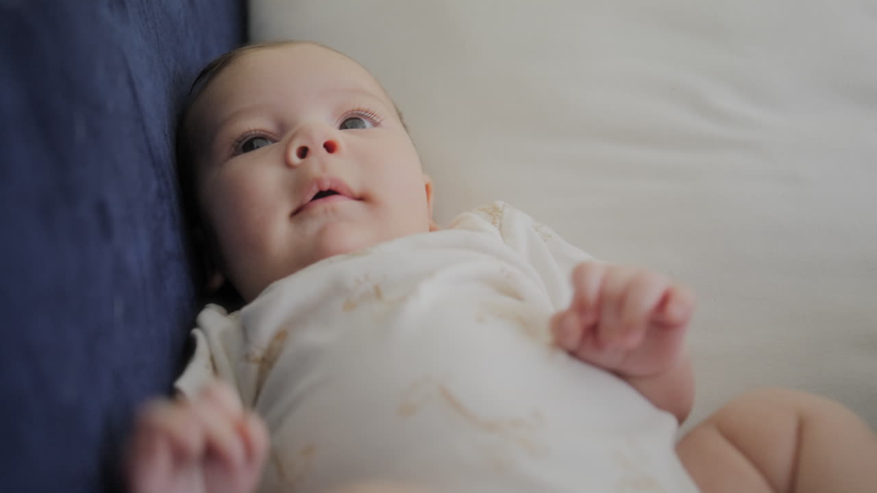 Premium stock video - Baby boy laying down on couch looking at camera