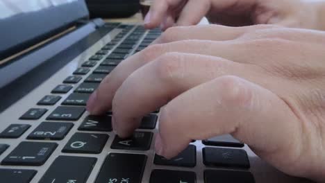 Close-up side view of female hands actively typing on a laptop keyboard.