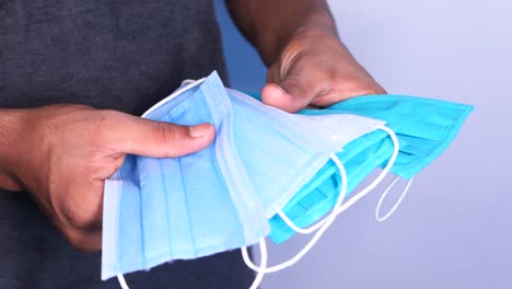 persona que sostiene varias máscaras faciales de colores