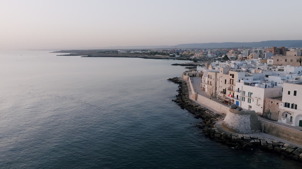 imágenes aéreas girando alrededor de la ciudad costera de monopoli, italia mostrando los edificios que están justo en las aguas del mediterráneo