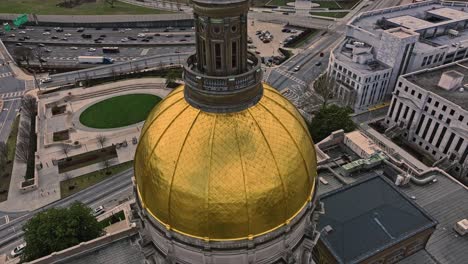 aerial tilt up shot showing golden cupola of georgia capitol museum with traffic at highway in atlanta during golden hour