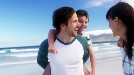 Parents-giving-piggyback-ride-to-their-children-at-beach