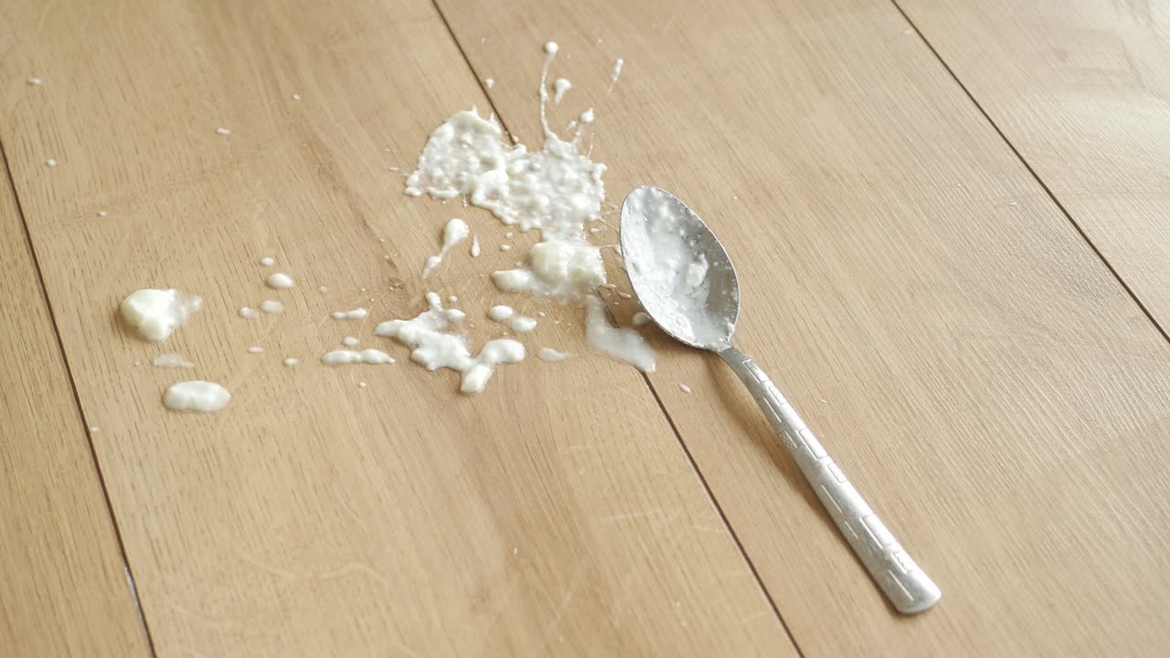 A spoon and spilled food on a wooden table