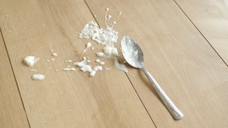 a spoon and spilled food on a wooden table