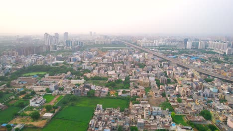 aerial drone shot flying over densely packed houses homes, buildings with sohna expressway passing through the middle showing cityscape of gurgaon delhi