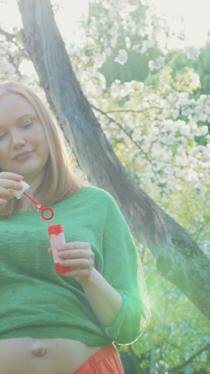 Pregnant woman blowing bubbles outdoors