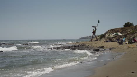 looking along the coast toward cala de mijas with a life guard sitting in her station by the rocks as holiday makers enjoy the sun