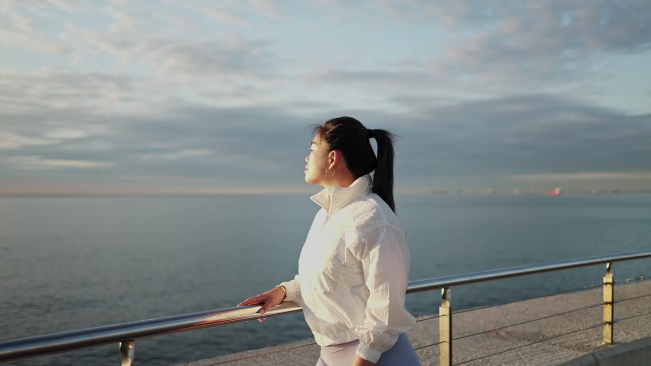 プロムナードから海を眺める若い女性