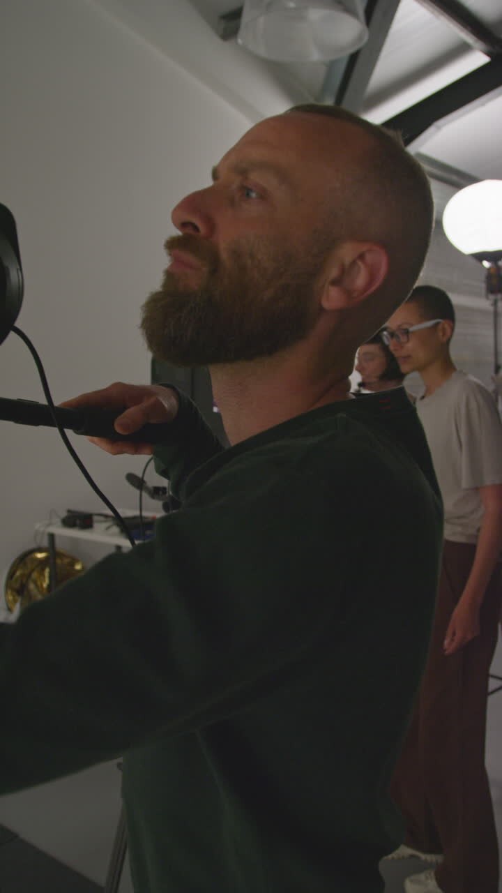 Vertical Video Of Crew Shooting Movie Or Video In Studio With Female Director Film Cameraman Sound Recordist And Assistant