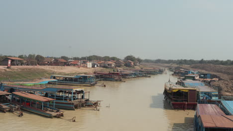 low flying shot along muddy river with fisherman boats in cambodia