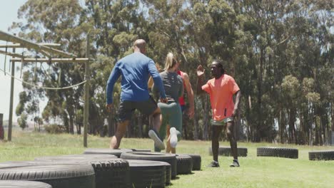 Diverse-fit-group-running-through-tyres-and-high-fiving-in-the-sun-at-obstacle-course