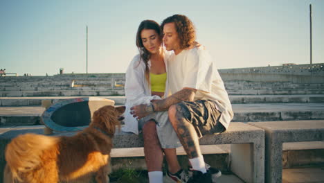 loving teenagers embracing urban bench. two skaters dating stadium at summer