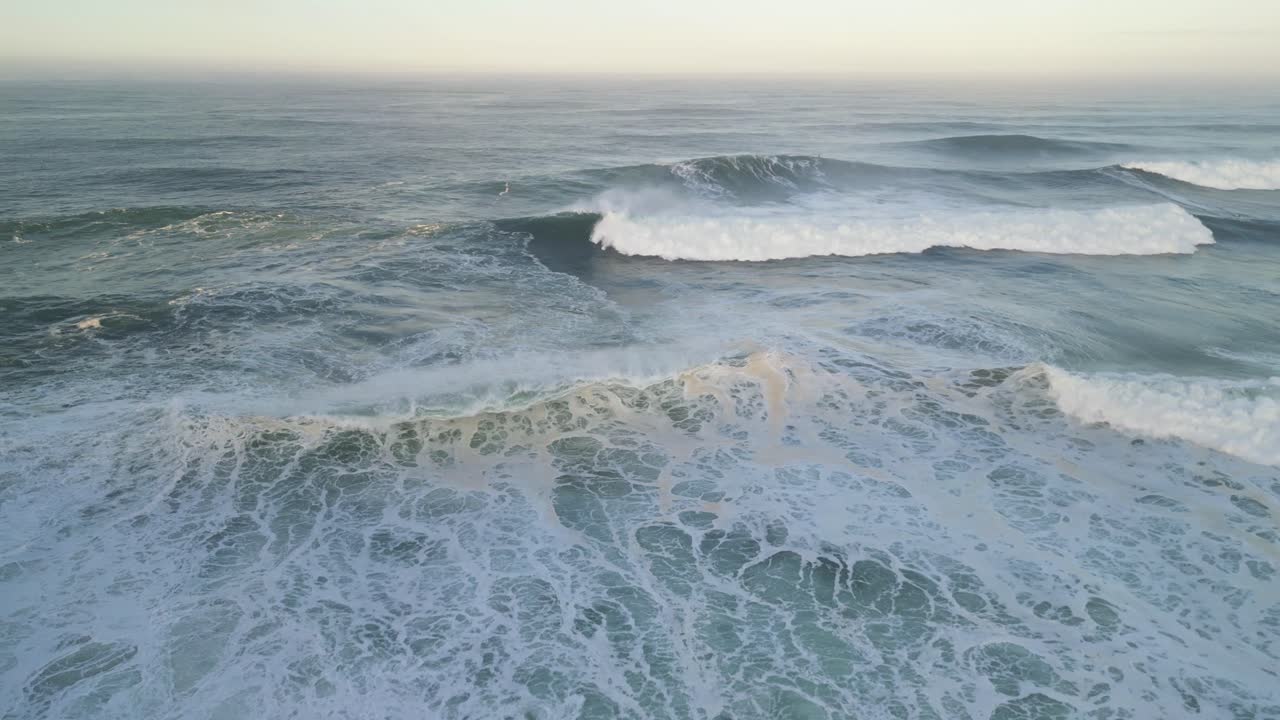 Waves crashing at sunrise in the waters near the Farol de Nazaré in Portugal
