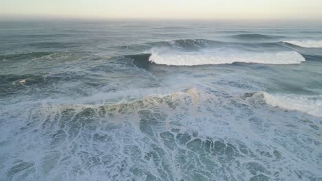 waves crashing at sunrise in the waters near the farol de nazaré in portugal