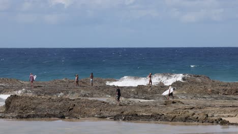 people enjoying and exploring a rocky seaside