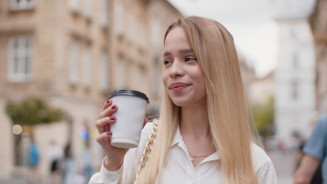 Young woman girl enjoying drinking morning coffee hot drink relaxing taking a break in city street