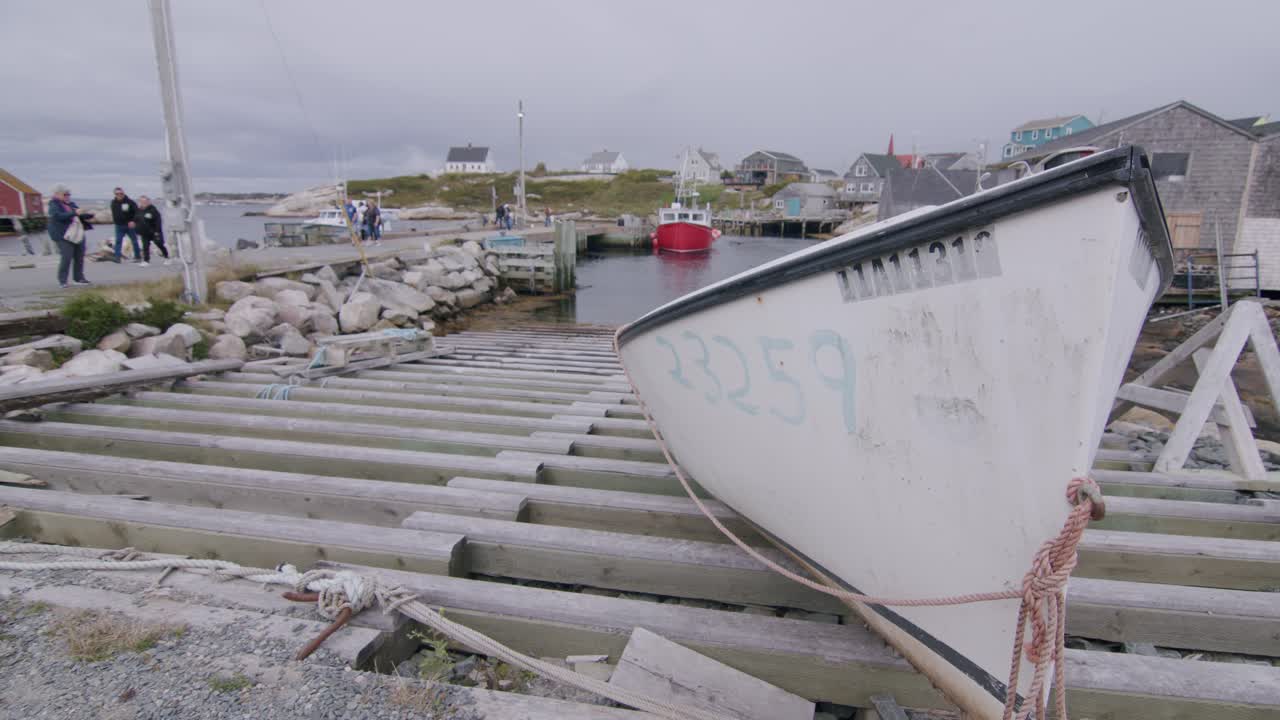 Harbor scene at Peggy's Cove with tourists and boats on a cloudy day in a small fishing village