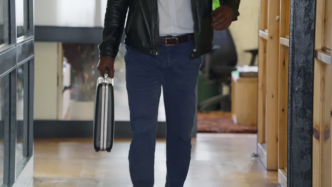 Agent man walking with black briefcase in hand wearing leather jacket and jeans. Business transaction or travel for secret deal in corporate office. Mysterious negotiation or undercover deal operation