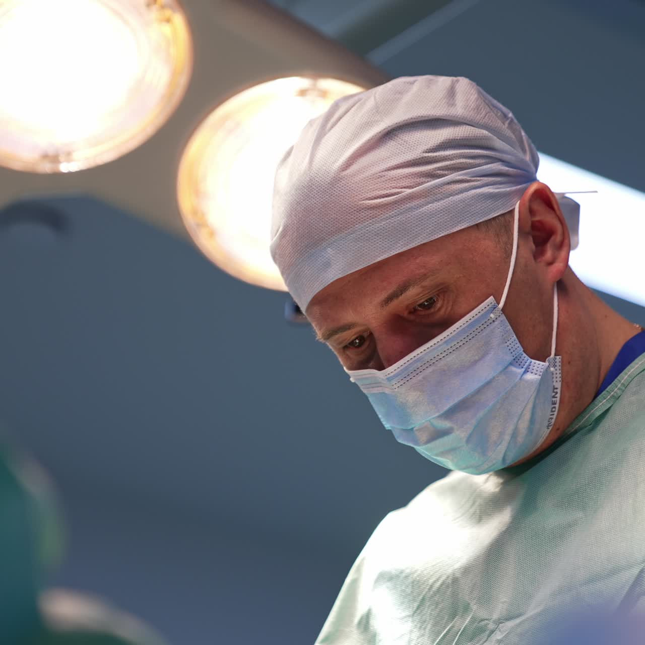 Senior surgeon turns his head for a moment from the operated patient. Portrait of a focused doctor concentrated on his work