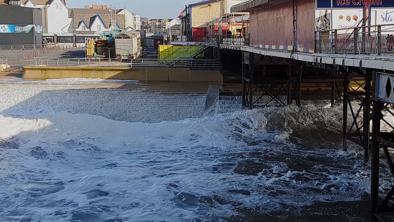 View along Blackpool Pier towards the shore. The waves have been strengthened by the storm causing them to crash into the sea wall under the pier.