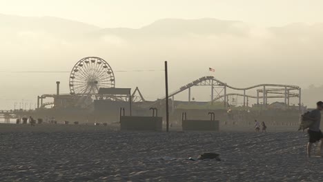 un hombre camina en la arena frente al muelle de santa monica en santa monica california