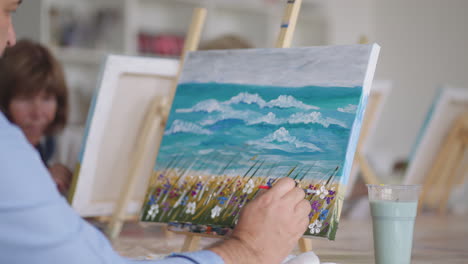 close-up of an elderly man painting a picture with a brush