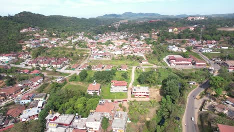 View-from-above-of-a-hill-station-showing-populated-areas,-vehicles,-and-a-green-environment