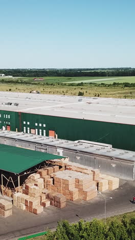 a factory for manufacturing a parquet board is in the middle of the field. aerial view. vertical video