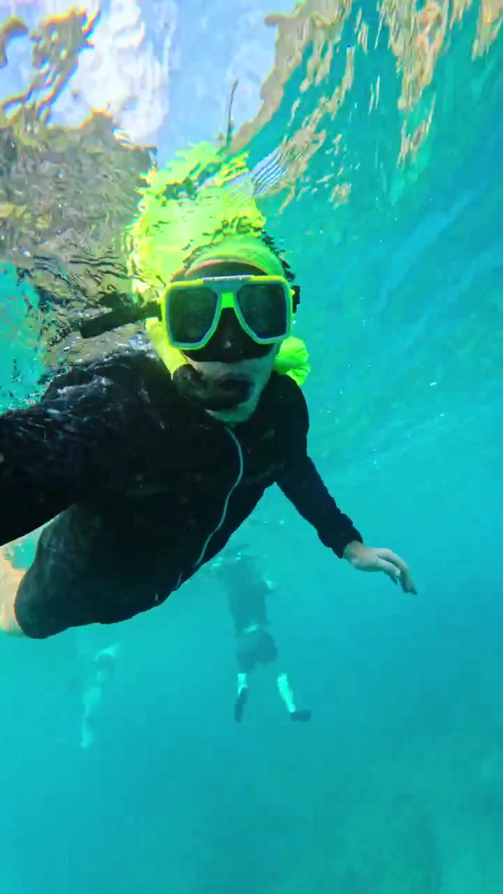 Um praticante de snorkel explora águas tropicais vibrantes sob reflexos cintilantes da luz solar.